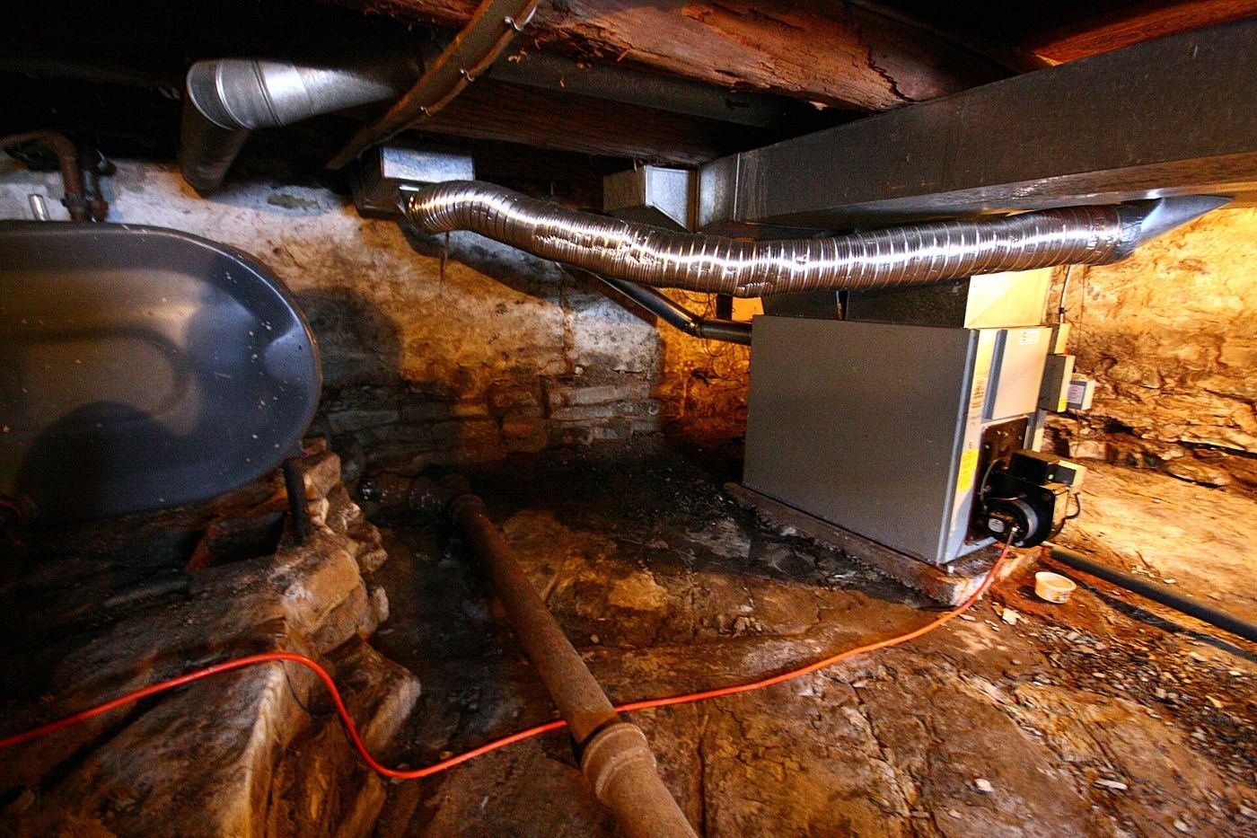 Old stone basement with pipes and ductwork
